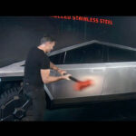 Franz von Holzhausen hitting the Tesla Cybertruck with a sledgehammer at the unveil (door handles visible).