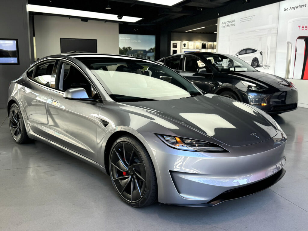 Front fascia of a Tesla Model 3 Highland in Quicksilver color inside a Tesla Store in the United States.