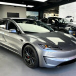 Front fascia of a Tesla Model 3 Highland in Quicksilver color inside a Tesla Store in the United States.