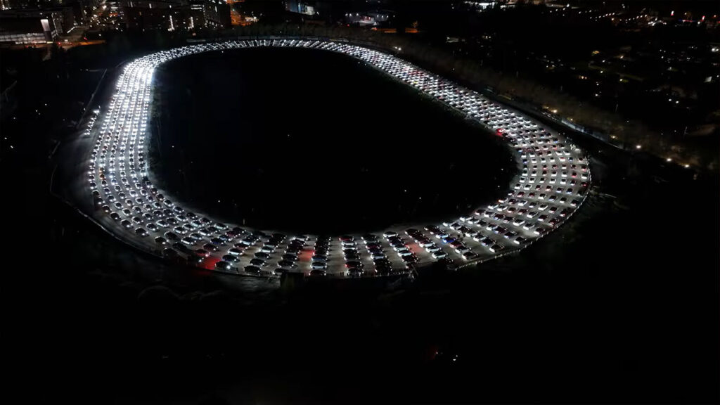 Screenshot: 902 Tesla vehicles perform a synchronized light show inside a stadium in front of a large audience and stunning images caught by a drone camera.